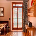 Raum mit Holzboden, Fenster zum Balkon und Küchenmöbel.