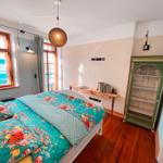 Schlafzimmer mit Doppelbett, Holzboden und Fenster mit Blick auf Wasser.