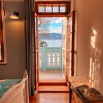 Schlafzimmer mit Blick auf See und Berge durch offene Balkontür.
