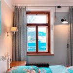 Schlafzimmer mit Fenster, Vorhängen und Bett mit floraler Bettwäsche.