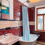 Bad mit freistehender Badewanne, Duschvorhang und roten Fliesen.