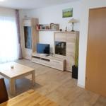 Living room with wooden furniture, TV, and large windows.