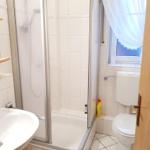 Bathroom with shower, toilet, and sink. Window with curtain.