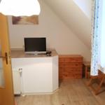 Room with sloped ceiling, TV, wardrobe, and wooden floor.