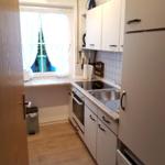 Kitchen with white cabinets, stainless steel sink, and window with curtains.