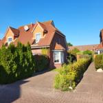 House with red tiled roof and paved path through green hedge