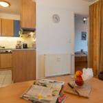 Küche mit Holzschränken, Essbereich mit Tisch und Stühlen, Blick in Schlafzimmer