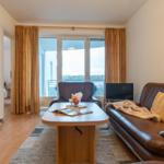 Wohnzimmer mit Sofa, Tisch und Balkonansicht.