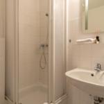 Bad mit Dusche, Waschbecken und Spiegel. Handtuch und Seife sind vorhanden.