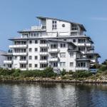 Modernes Mehrfamilienhaus an ruhiger Wasserseite mit Balkonen und Terrassen.