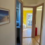 Hallway with wooden floor, door to bedroom and bathroom, wall picture with beach motif