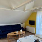 Living and dining area with sofa, dining table, and TV on yellow wall.