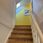 Wooden staircase with white railing and yellow wall with fish picture.