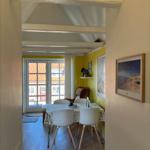 Dining room with table, chairs, and view to balcony. Yellow walls and wooden beams on ceiling.
