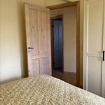 Bedroom with bed, wooden door, and wardrobe. Passage to another room.
