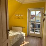 Bedroom with yellow walls, bed, and door to balcony.