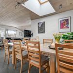 Dining room with wooden table and chairs, wall art, and plants. View into living area with seating.