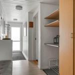 Hallway with wooden floor, white walls, and built-in shelves. Door to outdoor area visible.