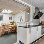 Kitchen with dining area, wooden table, white cabinets, and wooden ceiling.