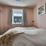 Bedroom with wooden walls, window, and bed with fur blanket.
