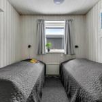 Two beds with gray bedding, window with curtains and wall art.