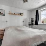 Bedroom with bed, nightstand, shelving, and window with view outside.