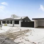 A modern house with a snow-covered yard and garage.