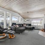 Living room with seating group, stove, and large window area. Wooden ceiling and carpeted floor.