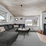 Living room with sofa, fireplace, and windows. Wooden ceiling and carpeted floor.