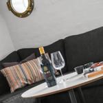 Living room with gray sofa, round table, and wine bottle.