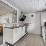 Kitchen with dining area, white cabinets, and wooden floor. Countertop, sink, and stove are present.