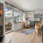 Wohnraum mit Kamin, Sitzgelegenheiten und Blick in die Küche.