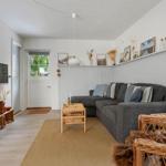 Wohnzimmer mit grauem Sofa, Holztisch und Wandregal mit Bildern.