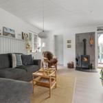 Wohnzimmer mit Sofa, Kamin und Fenster zur Terrasse.