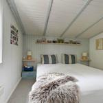 Ein Schlafzimmer mit einem Bett, zwei Nachttischen, einem Fenster und einer Decke.