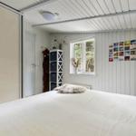 Schlafzimmer mit großem Bett, Fenster und weißen Wänden. An der Wand hängt eine Fotowand.
