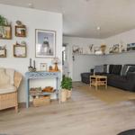 Wohnzimmer mit Sofa, Sitzgelegenheit und Wandregal mit Dekoration.