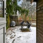 Von der Tür blickt man auf eine schneebedeckte Terrasse mit Tisch, Stühlen und Gartenmöbeln.