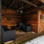 Holzveranda mit Sitzgruppe und Fenster. Schnee liegt auf dem Boden.