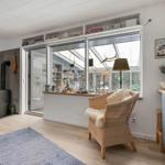Wohnbereich mit Holzboden, Kamin und Sitzgelegenheit vor großem Fenster.