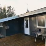 Haus mit Terrasse, Tisch und Stühlen, umgeben von Bäumen.