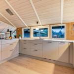 Küche mit Holzdecke, Fenstern und modernen Schränken.