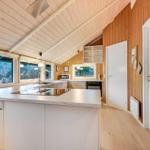 Küche mit Holzwand, Arbeitsplatte und Fenstern zum Wald