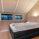 Schlafzimmer mit Holzwänden, Doppelbett und zwei Fenstern zur Aussicht.