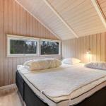 Schlafzimmer mit Holzwand und Dachfenster, Bett mit weißer Bettwäsche.