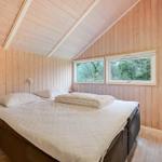 Schlafzimmer mit Holzwand, Bett und Fenster zum Wald