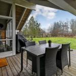 Terrasse mit Tisch und Stühlen, Blick auf grünen Rasen und Bäume.