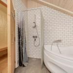 Bad mit Badewanne und Dusche, daneben Sauna mit Holzwand und -boden.
