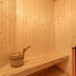 Sauna mit Holzwand, Sitzbank und Holzbucket mit Löffel.