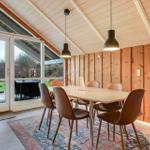 Esszimmer mit Holzwand, Tisch und Stühlen. Durchgang zur Terrasse mit Gartenansicht.
